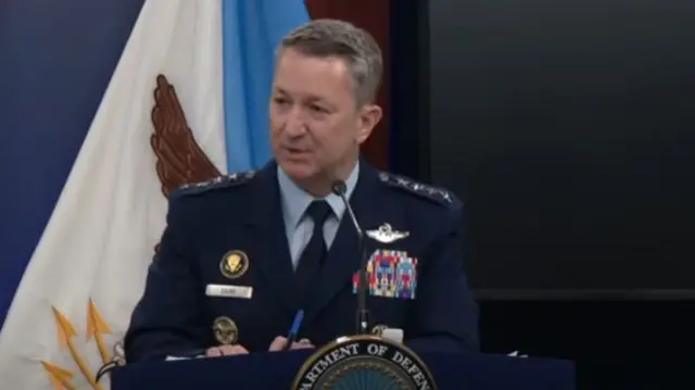 Dan Caine speaking at a podium
