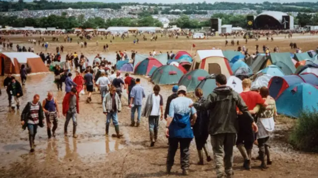 People walk through mud at Glastonbury festival in 1998.