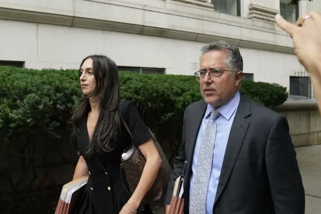 Teny Geragos (left) and Marc Agnifilo walk in front of a Manhattan court. both are dressed in business attire and are carrying stacks of documents