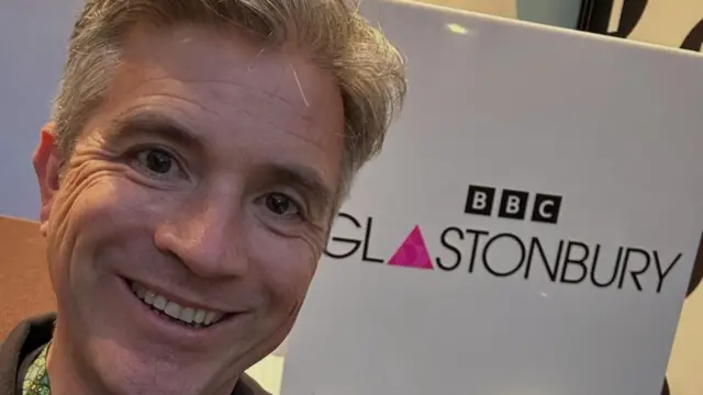 Mark posing in front of a BBC Glastonbury sign