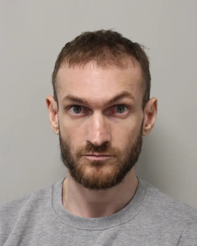 Mugshot of Marcus Monzo. He is staring directly towards the camera wearing a grey jumper