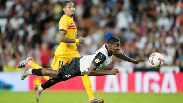 Cristhian Mosquera of Valencia clears the ball whilst under pressure from Raphinha of FC Barcelona