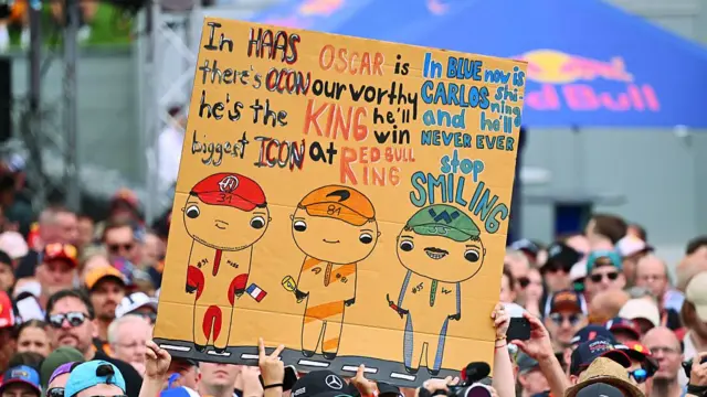Fans hold a sign for Esteban Ocon, Oscar Piastri and Carlos Sainz