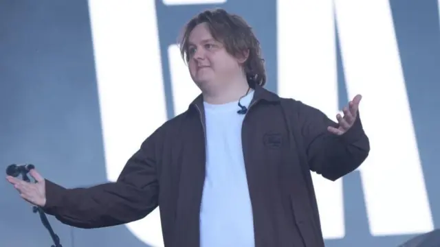 Lewis Capaldi on stage, with his arms open as he gestures on stage