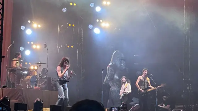 The Blossoms playing on stage in front of a large gorilla