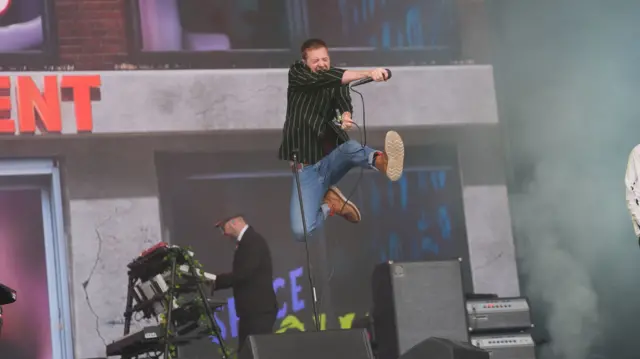 Kaiser Chiefs frontman Ricky Wilson jumps high in the air while holding a microphone while performing on the Pyramid Stage during the Glastonbury Festival