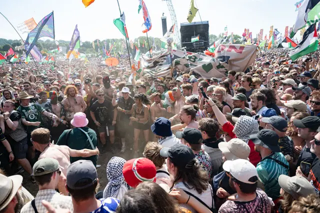 Hundreds of people form a mosh pit in a packed crowd for Kneecap