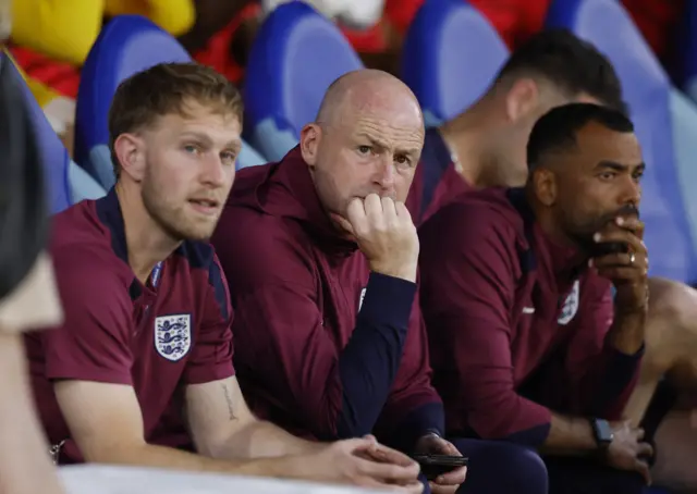 Carsley leans his chin on his hand on the bench