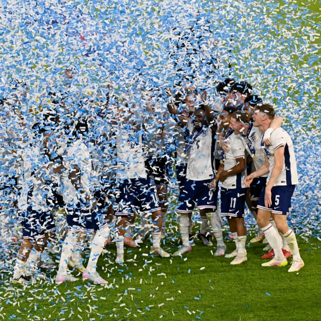 England players are covered in confetti as they lift the trophy