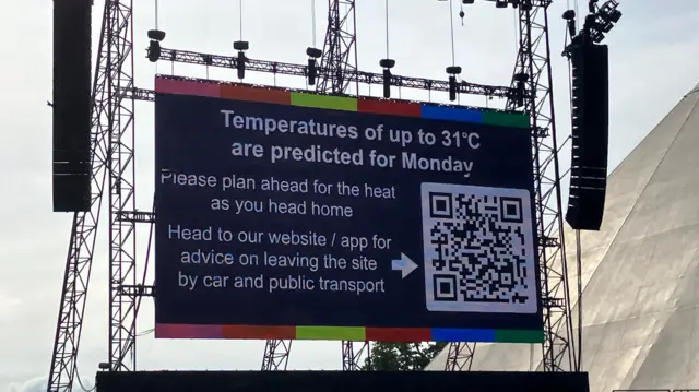 A screen in Glastonbury displaying a heat alert message with a picture of a QR code