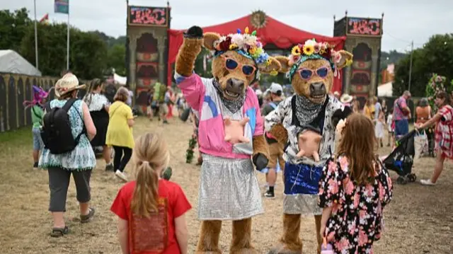 Performers wearing dog costumes entertain two young girls on the Circus Field