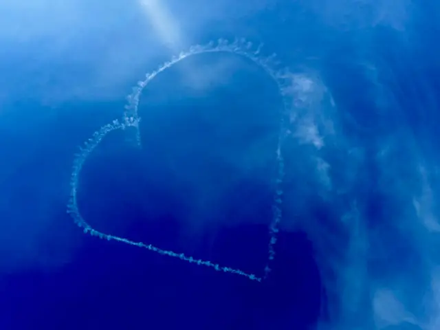 A photograph of a heart-shaped trail left by an aircraft during Nile Rodgers' set at Glastonbury