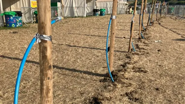 A photo of a field with hosepipes that have been attached to wooden posts