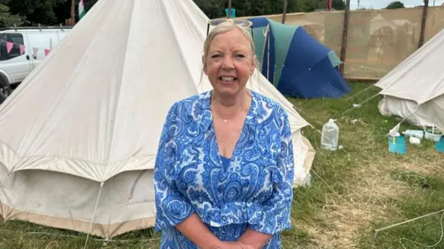 Deborah Meaden in blue sitting in front of bell tent