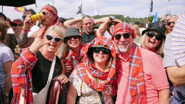 5 people with a red and white tartan scarves in the crowds