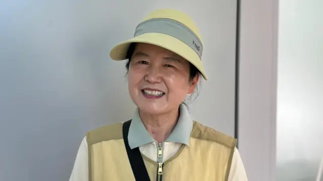 South Korean voters Kwon Soon-oh, wearing a beige hat and vest, smiles at the camera.