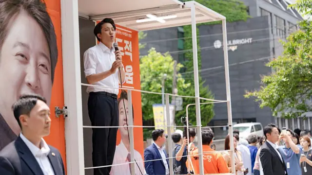Lee Jun-seok, dressed in white shirt and black trousers, speak in front a crowd during his campaign