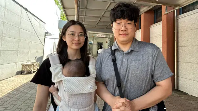 Woman carrying baby standing beside her husbabnd in Seoul South Korea