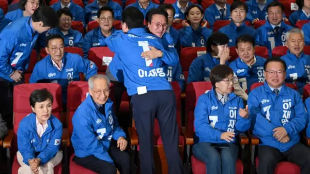 Two DP members embrace each other as results come in