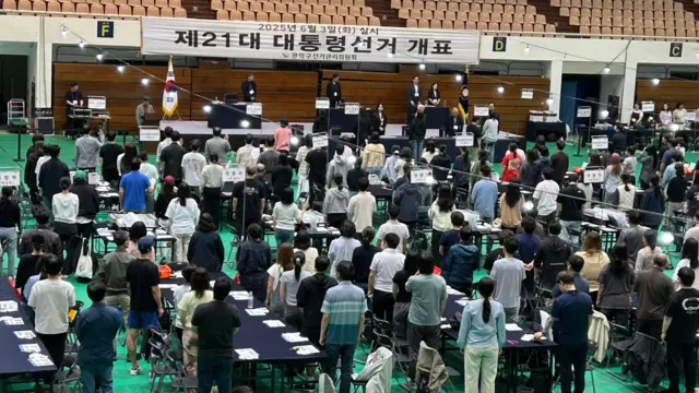 Vote counters stand up for the national anthem at the vote-counting centre