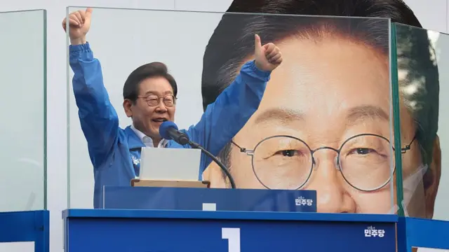 Lee Jae-myung speaks behind bulletproof glass during a campaign rally in Seoul on 29 May 29