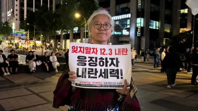 A woman standing in a square holding a sign