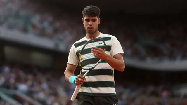 Carlos Alcaraz inspects his racket