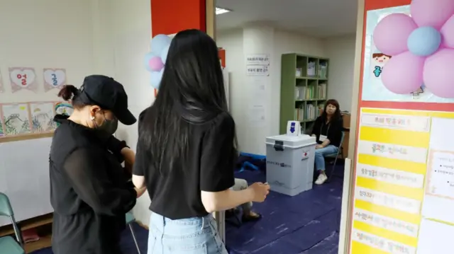 Two women walk into a polling station at a day care centre in South Korea.
