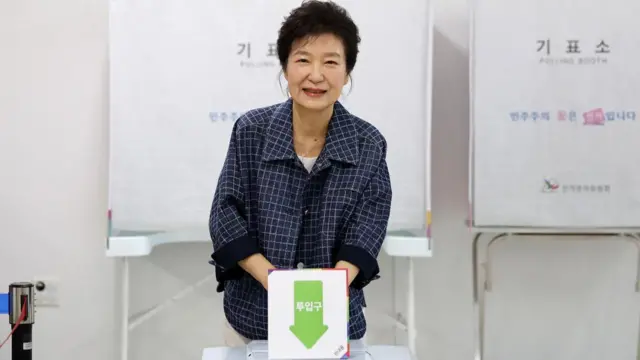 Park Geun-hye, dressed in a blue jacket, smiles at the camera while casting her vote