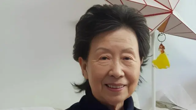 Hong Sook-ja looks at the camera, with a star-shaped light behind her.