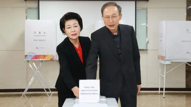 Lee Myung-bak and his wife, dressed in black suits, put their ballots in the voting box