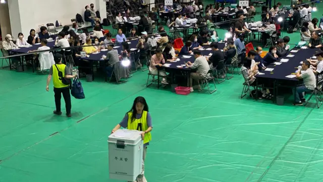 Vote counting is underway inside the Seoul National University. Counters sit along rows of navy tables and chairs