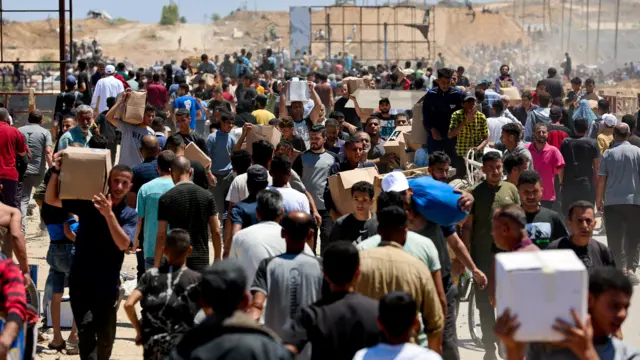 Palestinians carry aid supplies which they received from the U.S.-backed Gaza Humanitarian Foundation