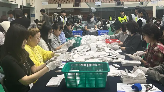 Officials go through stacks of ballot papers at a vote counting station in Seoul