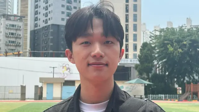 Ji-sung, 21, posts for a photo in an open field after casting his vote