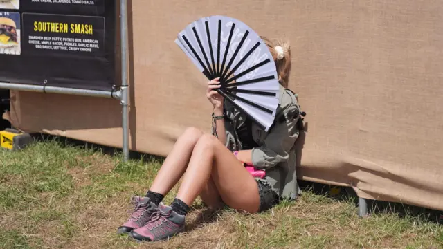 Woman fans herself in the sun at Glastonbury