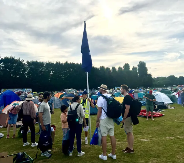 The stewards at Wimbledon Park direct people to the back of the queue
