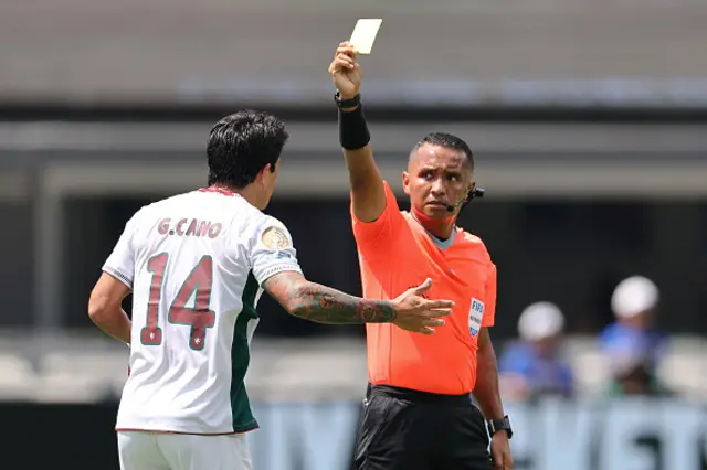 Referee Ivan Barton issues a yellow card to German Cano