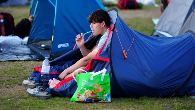 A man brushes his teeth in a tent