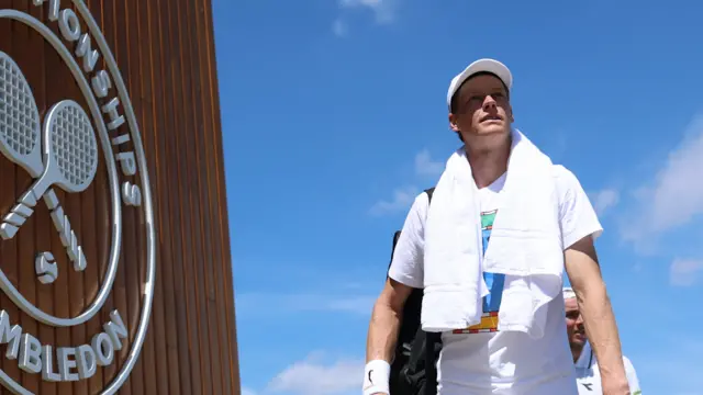 Jannik Sinner walks past Wimbledon sign
