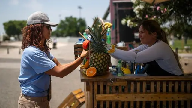 A tourist buys a watermelon juice near Torre de Belem garden during the first heatwave of the year, in Lisbon