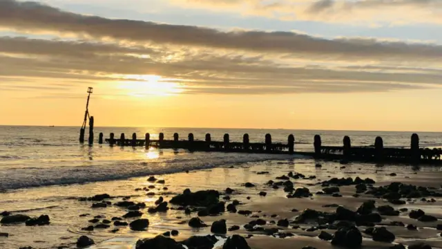Sun rises over the sea with an oil tanker in the background