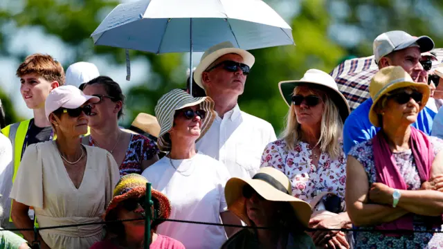 People wear hats and suncaps as they watch Wimbledon