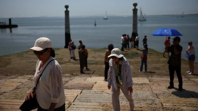 Tourists walk at Cais das Colunas as temperatures rise in Lisbon
