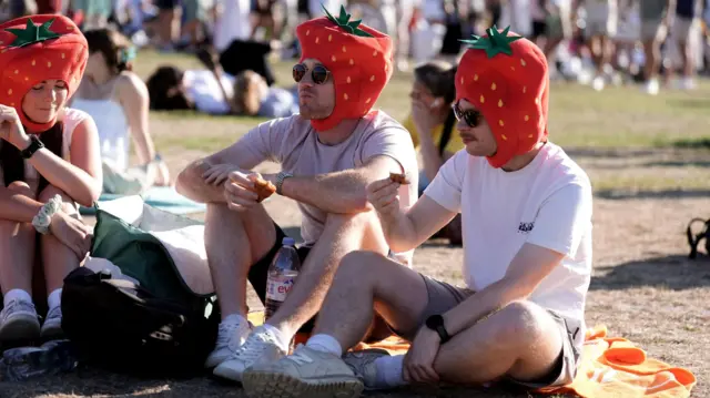 People wear strawberry hats in the Glastonbury queue