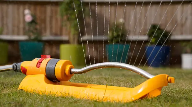A yellow garden sprinkler on the grass