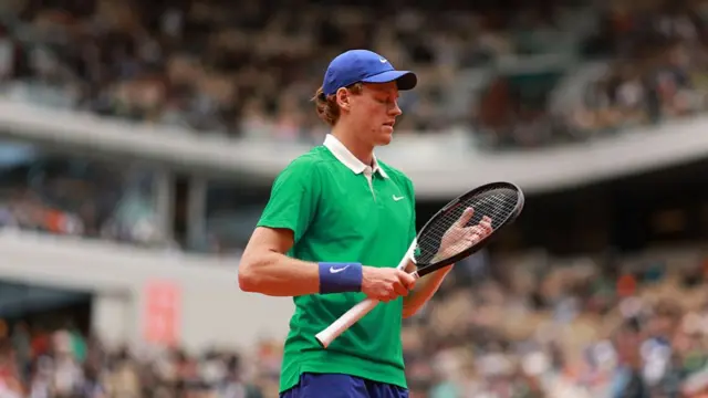 Jannik Sinner looks at his racquet