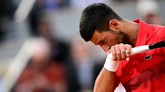 Novak Djokovic wipes his face