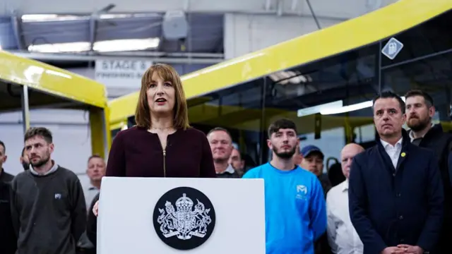 Rachel Reeves speaking from behind a lectern during a visit to Mellor Bus in Rochdale, Greater Manchester
