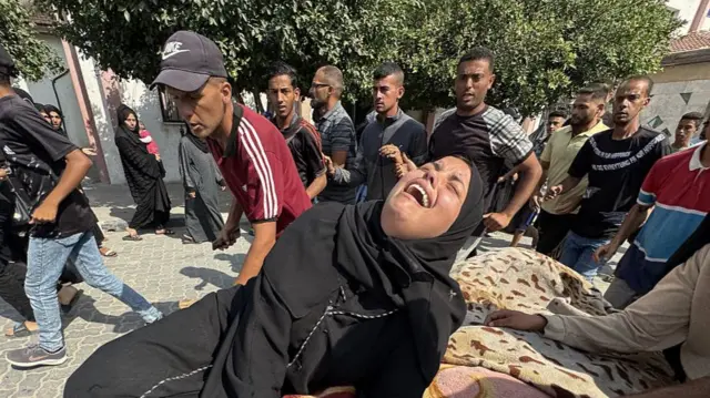A woman wails over a dead relative, whose body is covered by a blanket